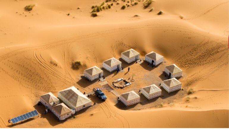 Luxury desert camp in the Moroccan Sahara surronded by sand dunes , seen from above