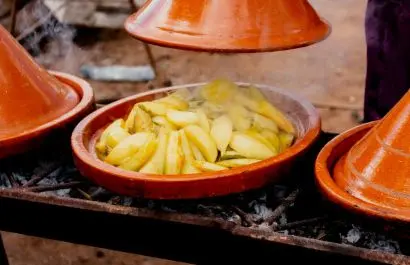 Tradional Moroccan tajine cooking over open fire during a local food experience